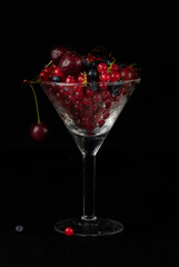 Summer berries in a glass glass on a dark background.