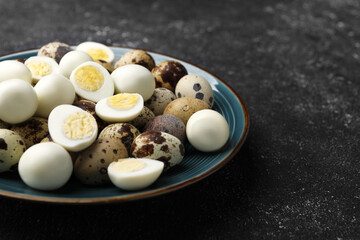 Peeled and unpeeled hard boiled quail eggs in plate on black table, closeup. Space for text