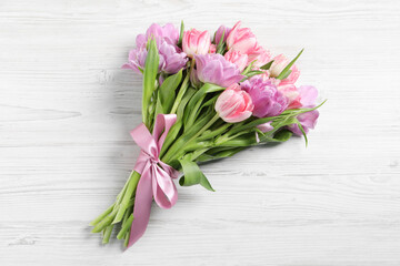 Beautiful bouquet of colorful tulip flowers on white wooden table, top view