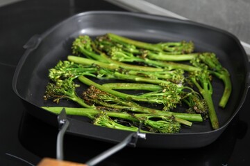 Grill pan with tasty cooked broccolini on cooktop, closeup