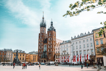 Fototapeta premium Old city center view with Adam Mickiewicz monument, St. Mary's Basilica and birds flying in Krakow on the morning. High quality photo