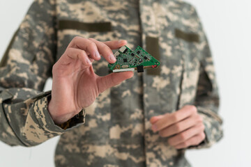 A military man is holding a chip electronic components. microcircuits, green camouflage.