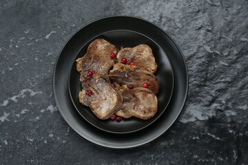 Tasty beef tongue pieces on black textured table, top view