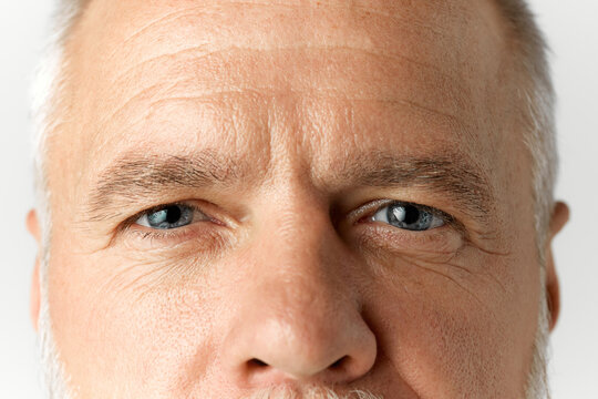 Close-up image of male face with blue eyes looking at camera. Vision care. Mature model with wrinkles on forehead. Health care. Concept of male beauty, face and skin care, daily procedures, age