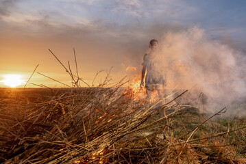 Fototapeta premium young guy crying in fire in burnt clothes, war, home destruction, human disappointment