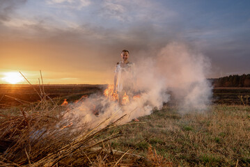 Naklejka premium young guy crying in fire in burnt clothes, war, home destruction, human disappointment