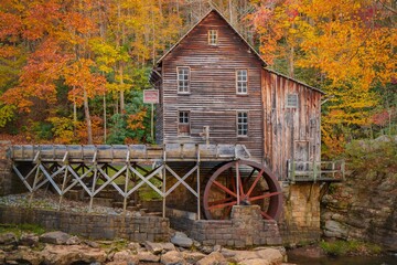 Old mill situated behind a waterfall surrounded by autumn foliage New River Gorge National Park