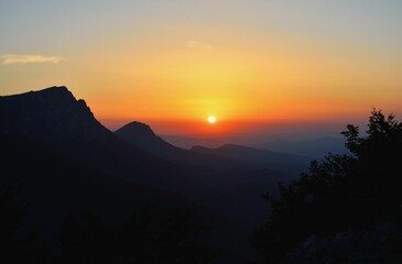 Aerial view of mountain landscape surrounded by groiwng trees during sunset