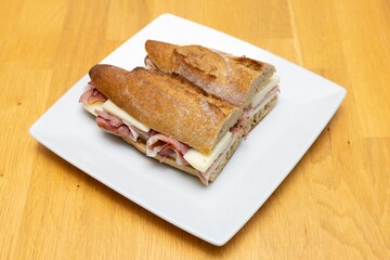 Two slices of Ham Sandwich put on a white plate on the kitchen table
