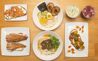 Top view of different meals with ramen, lemonades, and sandwiches on the kitchen table