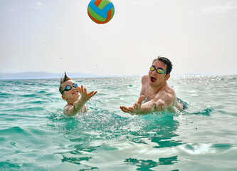 Happy family swim outdoors, father and son bonding, play ball, swim in the sea looking at view...