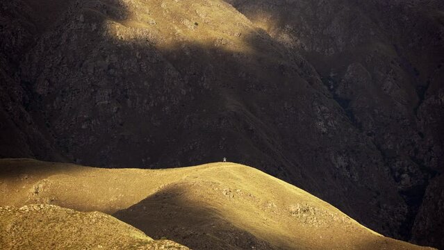 Time-lapse of cloud shadows over the mountains at sunset. Visible landmark at the top of a hill.