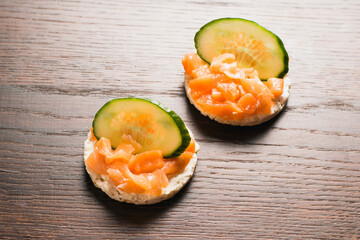 Sandwiches with red fish and cucumber. Salted salmon on crispy rice bread on a wooden background