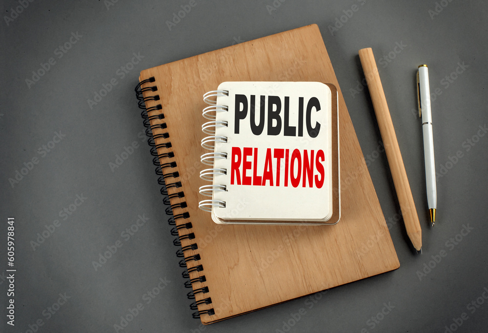 Poster public relations text on notebook with pen and pencil on grey background
