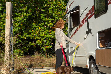 A woman filling the water tank of a motorhome.