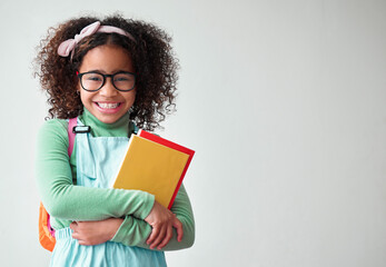 Obraz premium Education, smart and portrait a child with books for knowledge, reading and studying in a studio. Happy, smile and young girl kid student with glasses isolated by a white background with mockup space