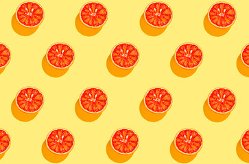 Creative pattern made with half of blood orange on bright yellow background. Summer fruit and...