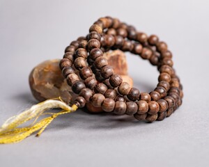 Obraz premium Wooden Mala prayer beads leaning on a stone, isolated on a purple background