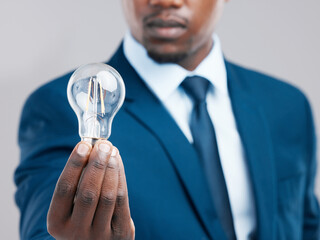 Energy, hand and businessman with light bulb for idea, knowledge or inspiration for corporate business strategy. Electricity, lightbulb and black man with creative solution, innovation or closeup