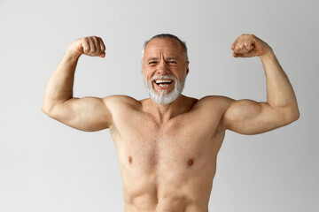 Portrait of handsome, fir, strong, mature, shirtless man with beard and gray hair showing muscles,...