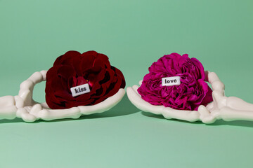 skeleton hands holding pink and red flower, in flowers words kiss and love, creative romantic concept, eternal love
