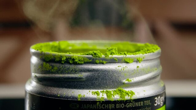 Close-up view of a hand opening a matcha tea jar
