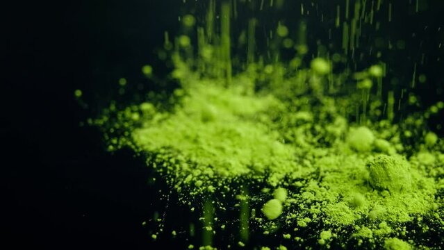 Close-up view of falling matcha tea powder on a black table