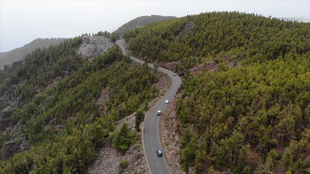 Aerial view of beautiful volcanic landscape with highway and cars driving along pine forest. 4K drone video. Volcano Teide, Tenerife, Canary islands, Spain. Footage during dust storm calima 