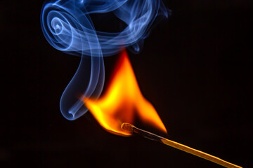 Flashed and burning wooden match on a dark background close-up. Bright fire and smoke from a...