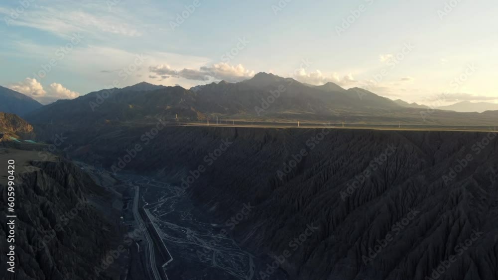 Sticker Drone view over dry river under green hills with rural houses with cloudy sky