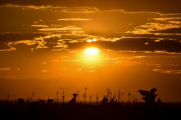 Fototapeta na wymiar Closeup of sunset with antennas from houses beneath it