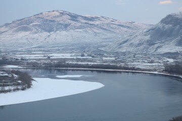 Fototapeta na wymiar Aerial shot of frozen lake near snow covered mountain peaks