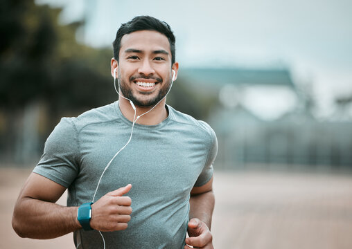 Fitness, portrait and man running with earphones for music, radio or sport podcast for motivation. Sports, exercise and male athlete runner doing outdoor cardio workout for race or marathon training.