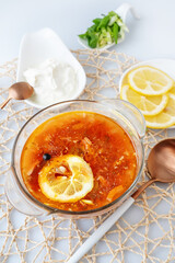 Meat Solyanka. combined solyanka. a portion of spicy red meat soup with tomatoes, smoked sausages and olives with lemon on a light background