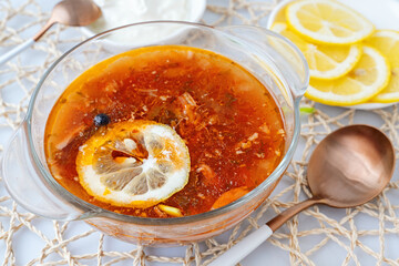 Meat solyanka. Hot combined solyanka. a portion of spicy red meat soup with tomatoes, smoked sausages and olives with lemon on a light background