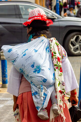 Baby being carried in manta blanket back pack in Otavalo, Ecuador - obrazy, fototapety, plakaty