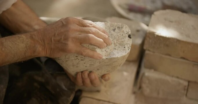A pottery master holds a stone of clay in his hands for the production of dishes in his workshop