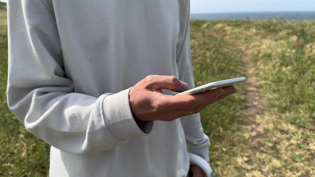 Close up view of male hands using smartphone scrolling, browsing, surfing internet, social media browsing slow motion