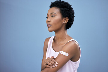 Fototapeta na wymiar Arm plaster, thinking and a black woman after the vaccine isolated on a blue background in a studio. Health, idea and an African person with a cover after vaccination for safety from covid virus