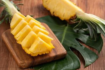 Fresh cut pineapple on a tray over dark wooden table background.