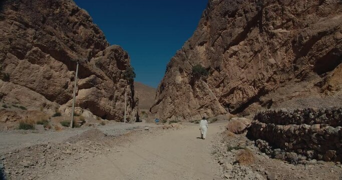 Back view of a man in walking on muddy road in between the mountains in Quetta Pakistan