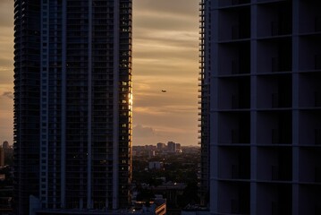 Airplane flying between two skyscrapers at sunset