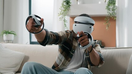 African American man having fun at home couch with virtual reality video game fight guy play 3d cyber gaming fighting with controllers man playing in VR glasses helmet using joysticks metaverse world
