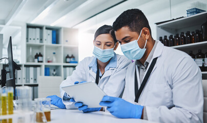 Science, tablet and team of scientists in a laboratory working on research for a medical project. Face mask, technology and healthcare researchers reading on medicine innovation with digital mobile.