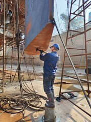 Shipyard worker is opening bottom plug of ship rudder