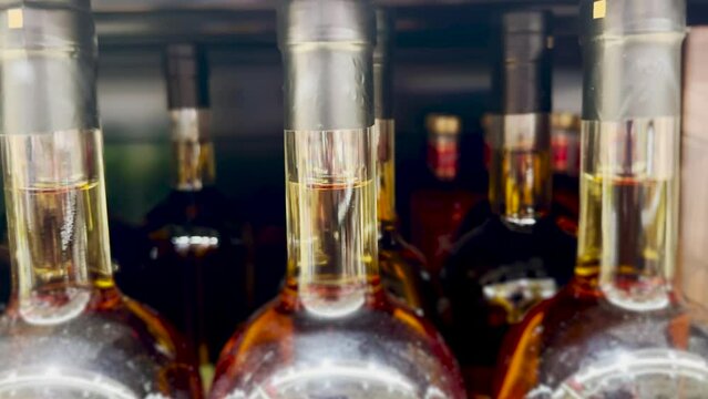 bottles of cognac on a shelf in a supermarket. alcohol sale problem of alcoholism in the world concept. bottles of whiskey a lot in the cellar lifestyle