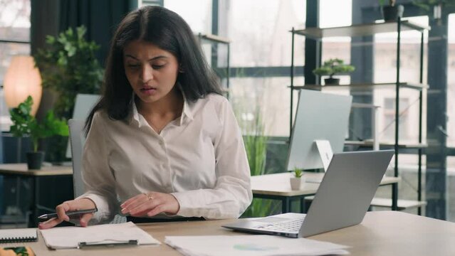 Arabian stressed businesswoman gen z Indian business woman working in office with computer laptop and paperwork problem failure search information trouble with documents difficulties financial mistake