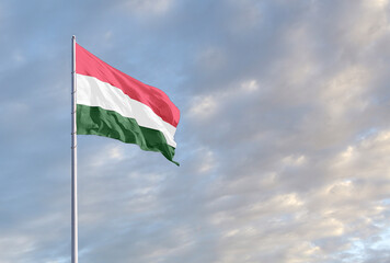 Waving Hungarian flag against a blue sky with clouds and empty space for text. Room for text.