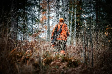 Foto op Canvas Hunter with gun in the forest © Petri Kettunen/Wirestock Creators