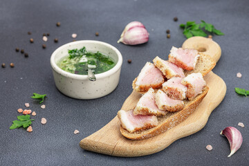 Canapes with rye bread and pieces of salty high-fat meat cooked with spices. Garlic sauce, snack